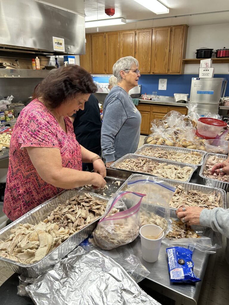 Volunteers in the church kitchen portioning turkey into foil pans