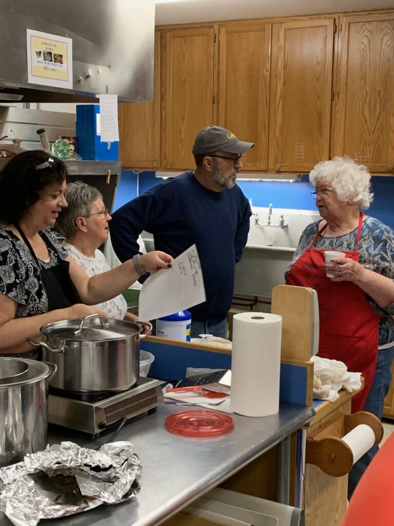 Volunteers chatting while preparing dishes in the church kitchen