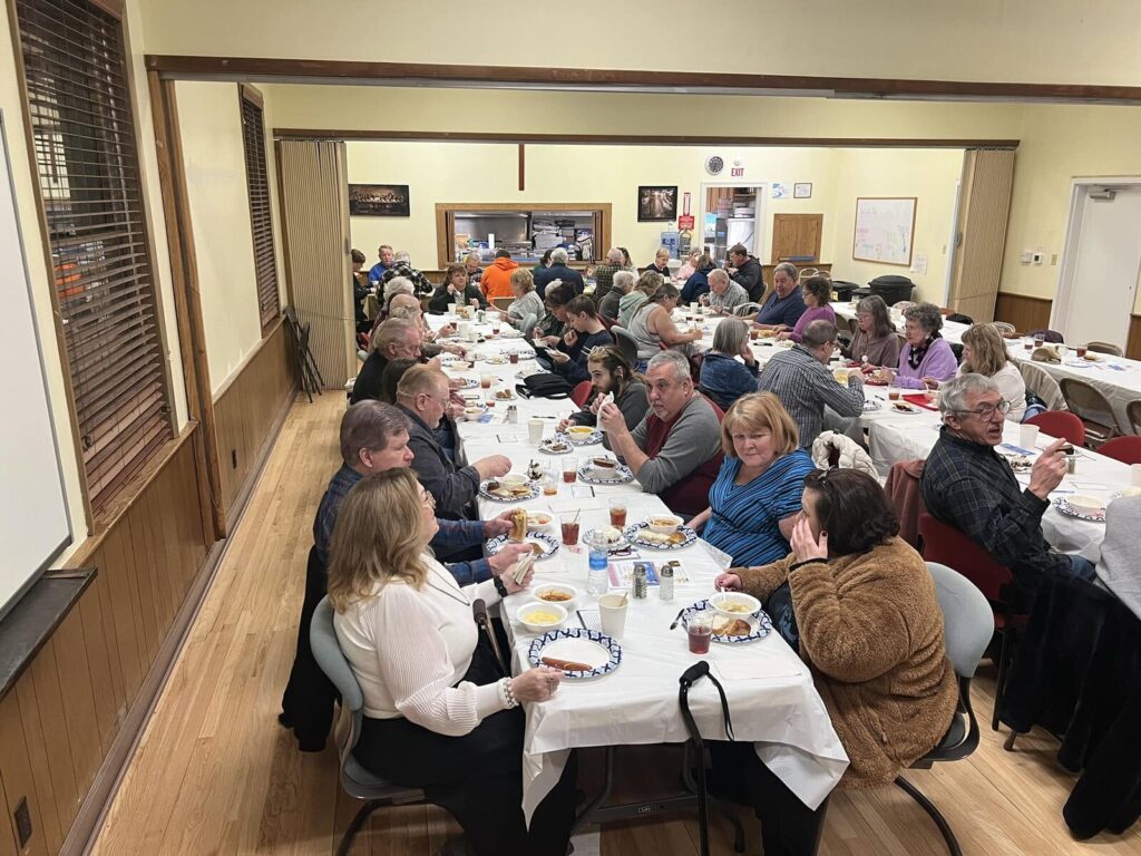 Guests seated at long white-covered tables during a community dinner