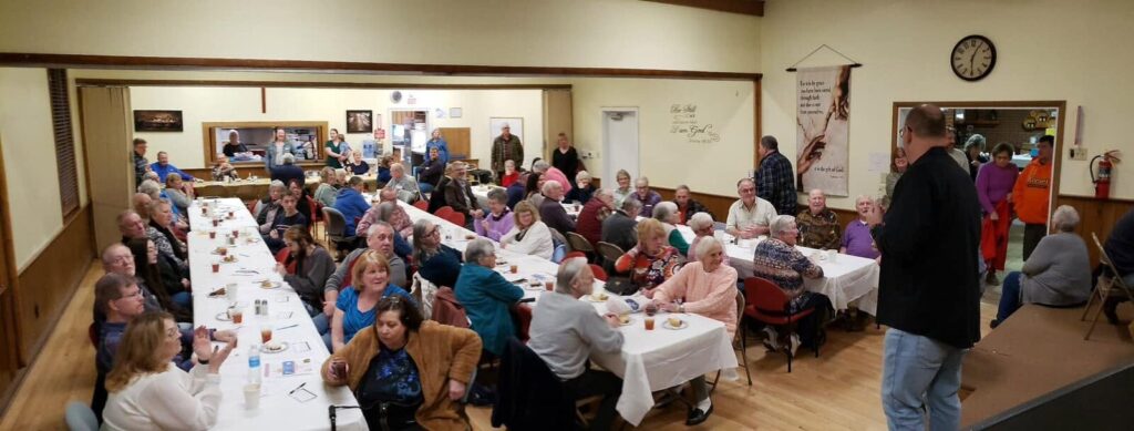 Wide view of the Fellowship Hall filled with dinner guests