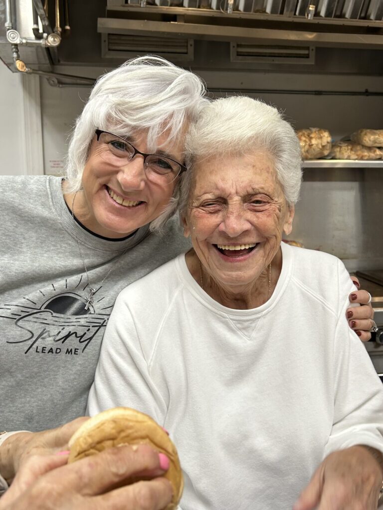 Two smiling kitchen volunteers posing together in the Union Chapel kitchen
