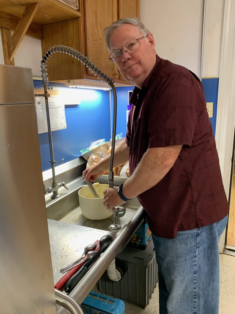 Volunteer washing dishes at the kitchen sink