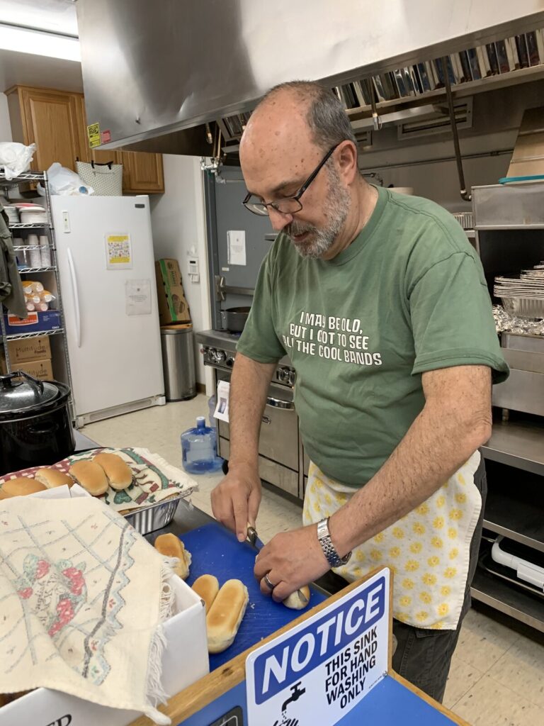 Volunteer in a green T-shirt preparing food at the kitchen counter