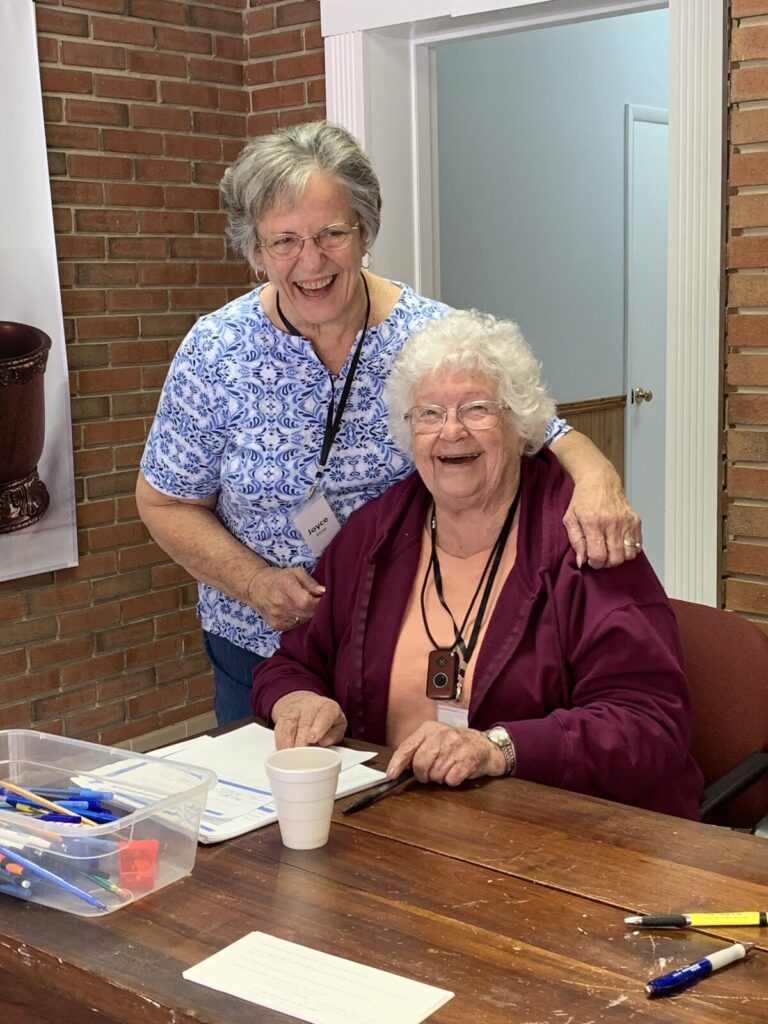 Two laughing volunteers at the welcome table