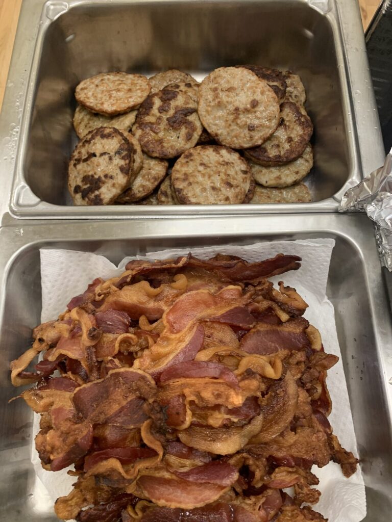Pans of sausage patties and crispy bacon