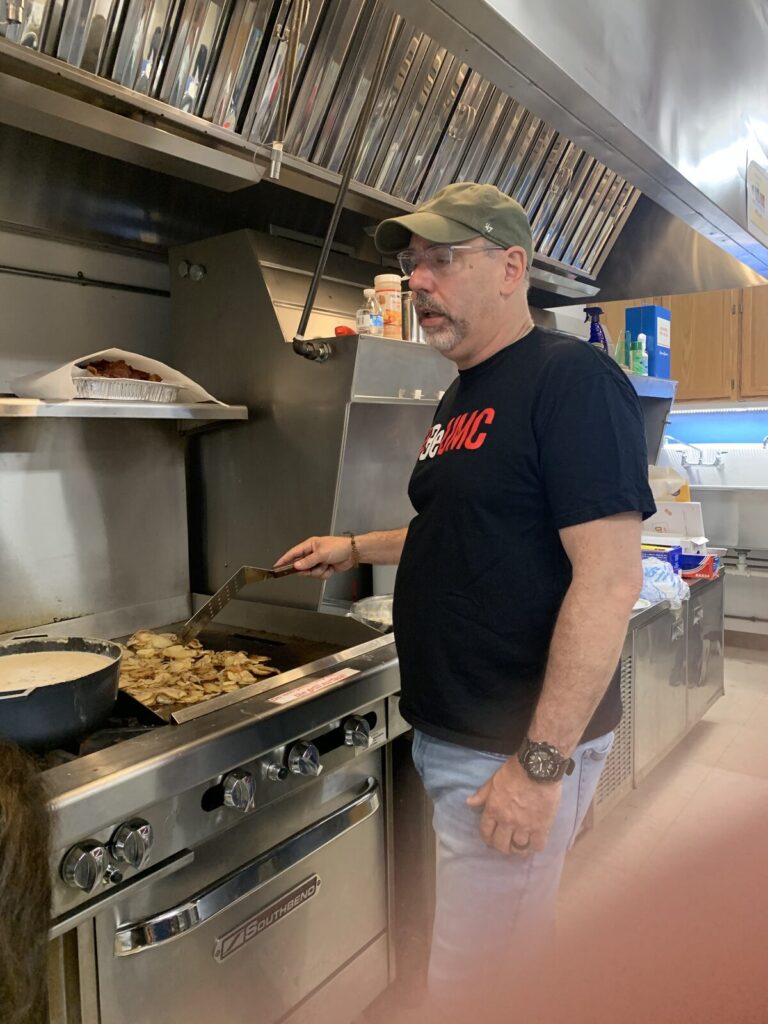 Volunteer in a cap cooking at the kitchen range