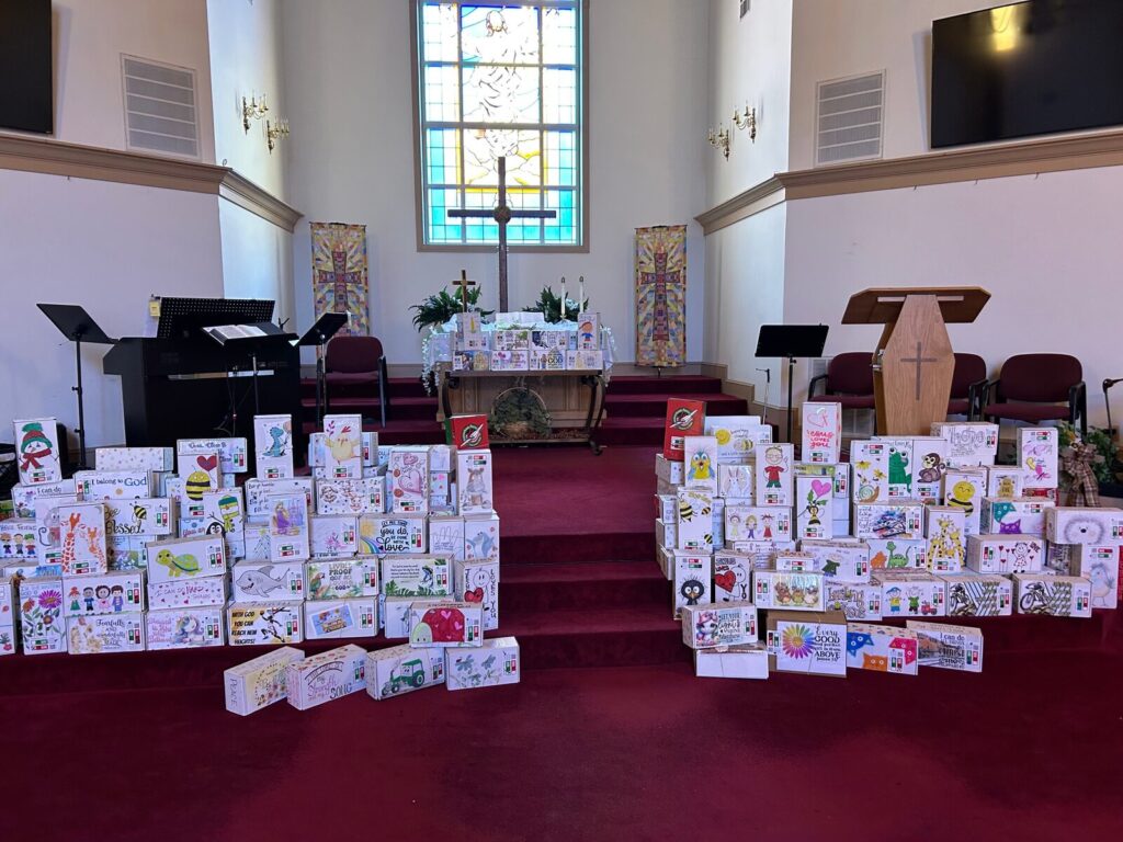 Hundreds of hand-decorated Operation Christmas Child shoeboxes lined up in front of the altar at Union Chapel
