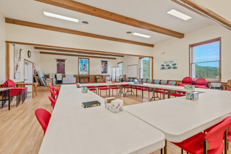 The fellowship hall set with tables and red chairs